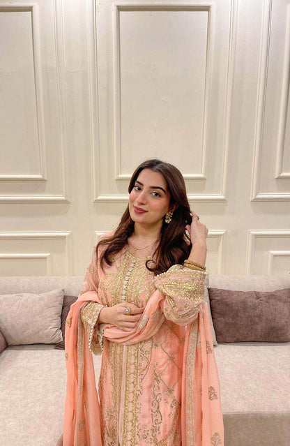 Peach embroidered long dress with gold detailing and sheer sleeves, standing pose
