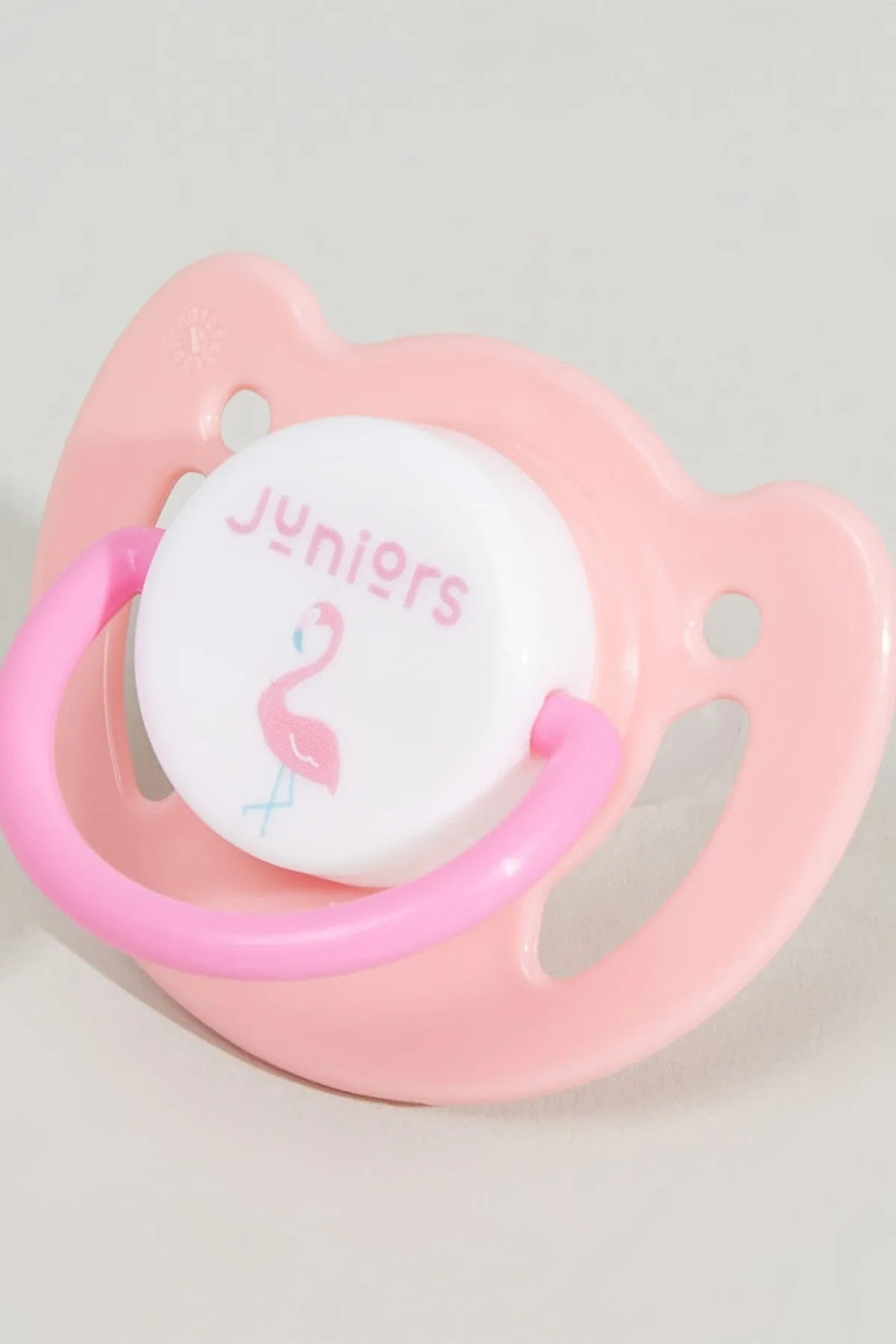 Pink pacifier with 'unicorns' graphic on clear shield, close-up front