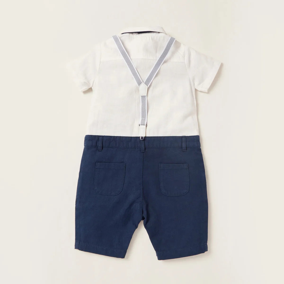 Baby romper back view with white top and navy shorts with suspenders