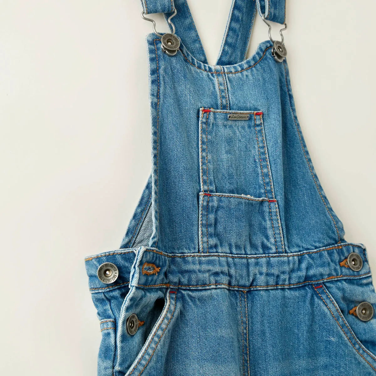 Close-up blue denim overalls with metal strap fasteners and chest pocket
