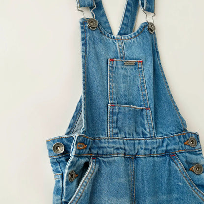 Close-up blue denim overalls with metal strap fasteners and chest pocket