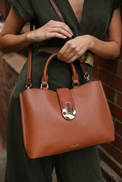 Brown leather tote bag close-up with metal clasp and stitched top handles