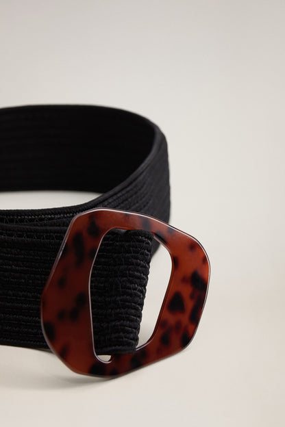 Close-up: black woven belt and tortoiseshell buckle