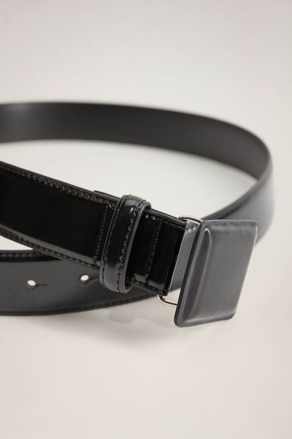 Black belt close-up with rectangular buckle, stitched keeper, and pin-hole row.