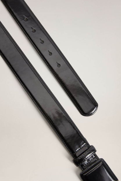 Black belt strap detail with stitched edges, multiple loops, and metal pin holes.