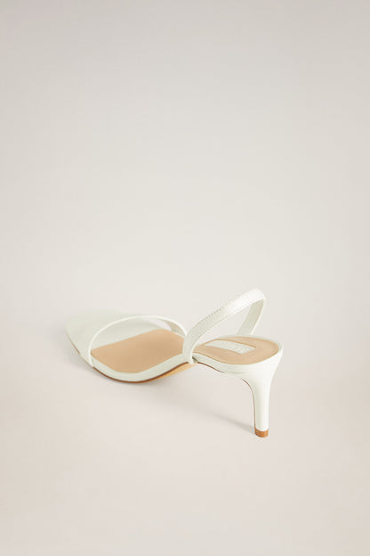Off-white heeled sandals with bow-style straps and open toe, stiletto heel.