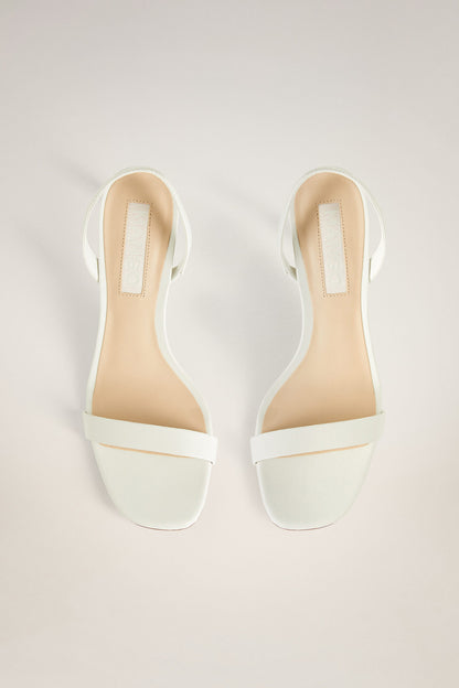 Off-white heeled sandals with open toe, V-cut straps, stiletto heel; pair view.