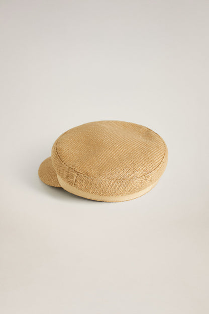 Sand straw-textured flat cap with short curved brim, angled view