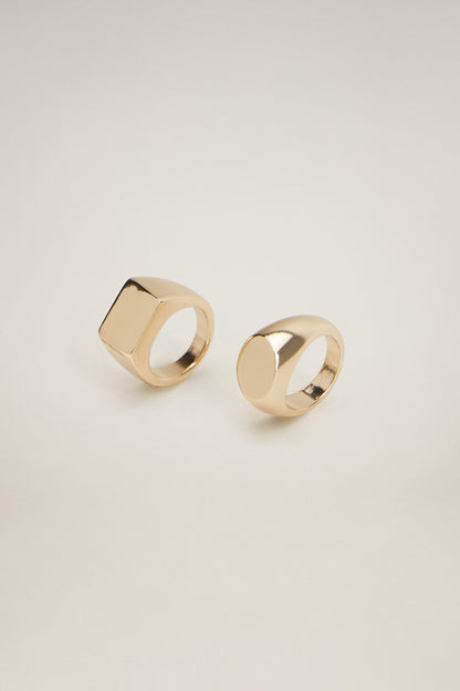 Gold-tone square signet ring and oval band ring, angled view
