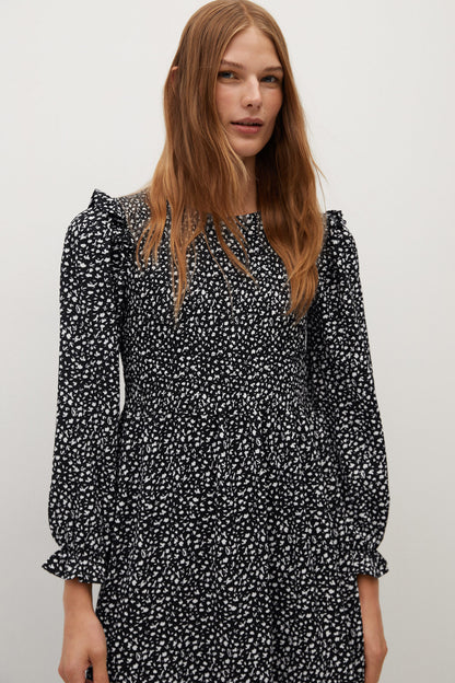 Black mini dress with white speckle print, V-neck, and long puff sleeves