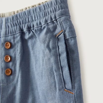 Blue baby pants close-up: elastic waistband with brown buttons and side pocket