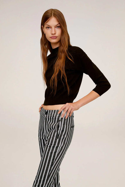 Black cropped knit sweater with striped capri pants, side profile
