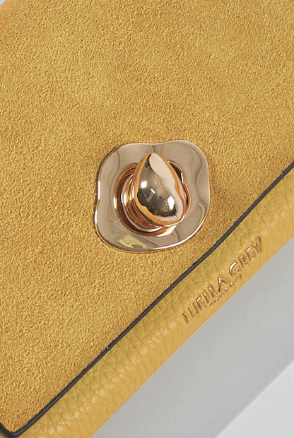 Close-up of yellow wallet corner with engraved edge trim and round metal snap