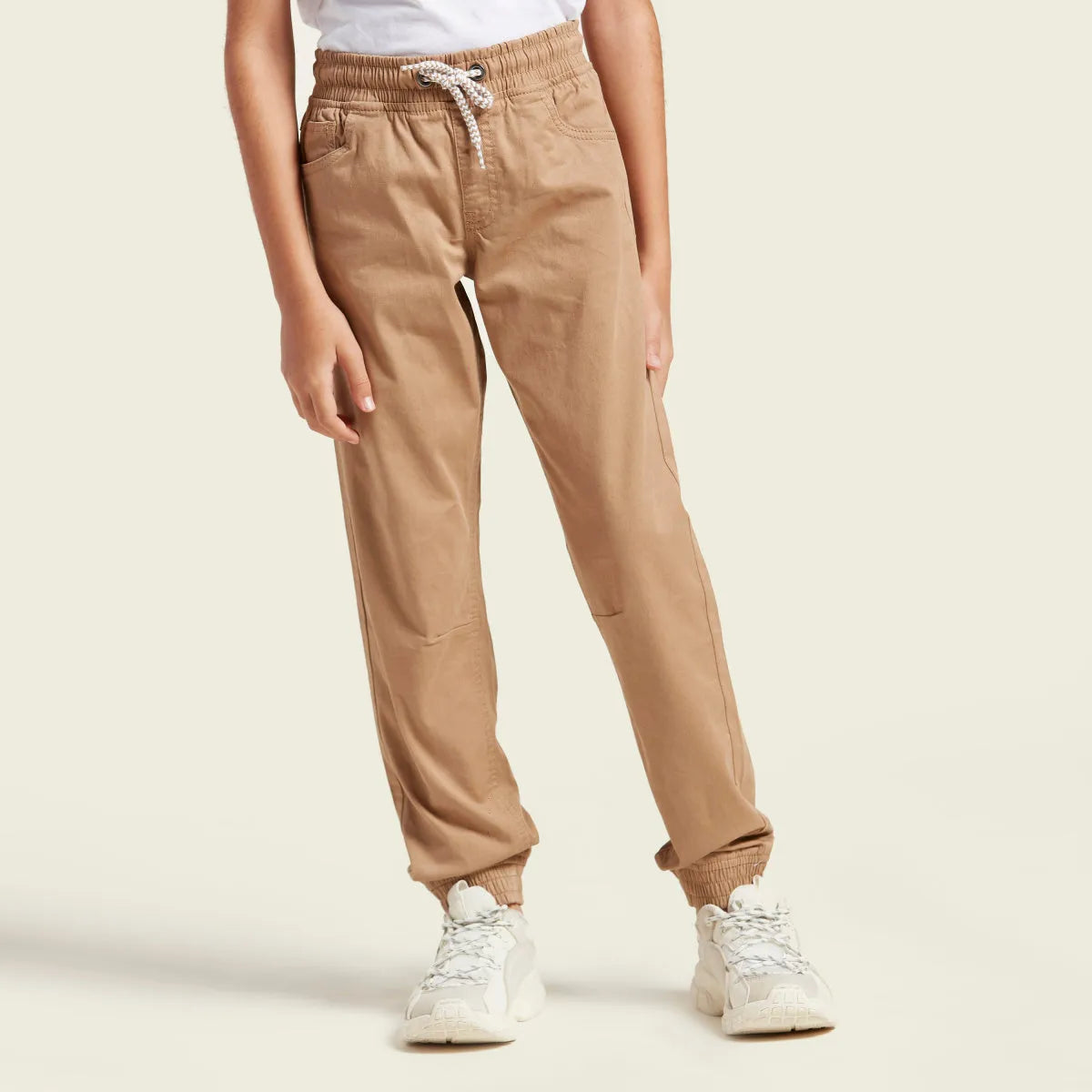 Beige jogger pants with elastic waist, drawstring, and relaxed tapered legs