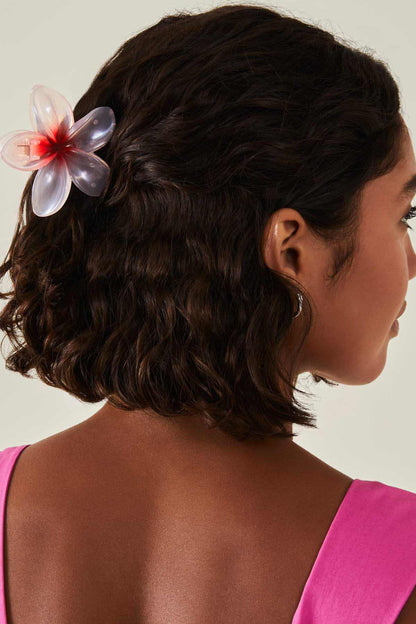 Pink flower hair clip on dark hair, with layered translucent petals