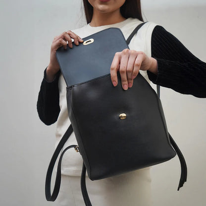 Dark gray flap tote with gold-tone clasp and front logo emblem, carried on shoulder