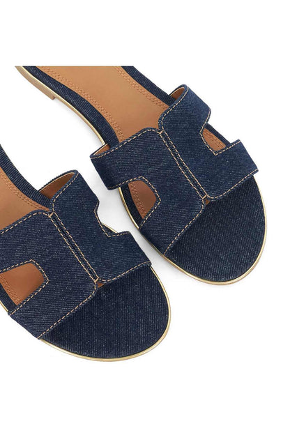 Close-up of navy denim slide sandal straps with contrast stitching and tan trim