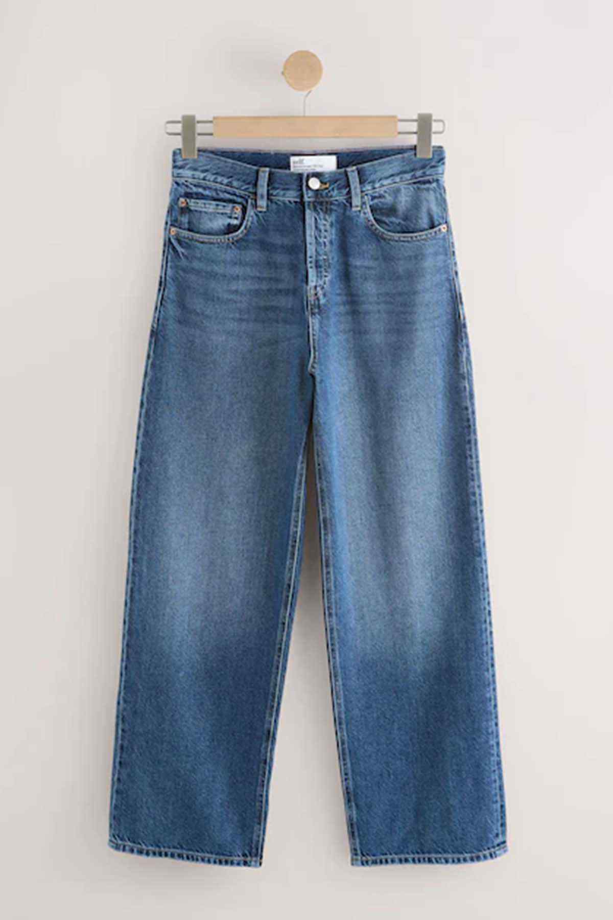 Dark blue denim jeans on hanger, wide-leg style with front button fly