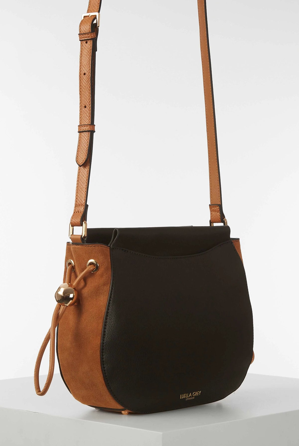 Black leather mini crossbody bag with tan shoulder straps and gold-tone rings