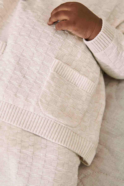 Baby knit sweater, light pink textured knit close-up with ribbed hem