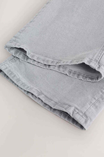 Folded light grey denim jeans with visible hem and seam stitching