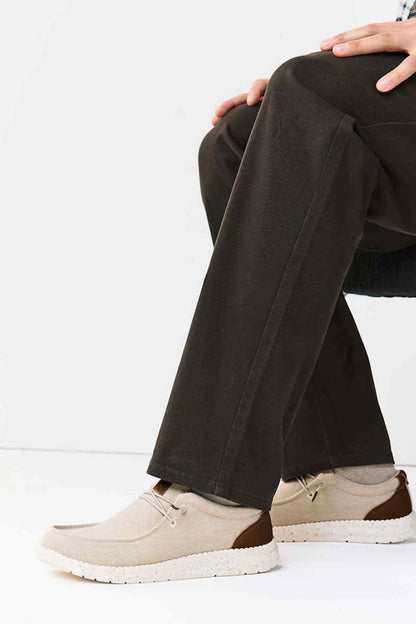 Dark straight-leg pants with beige lace-up sneakers, side view