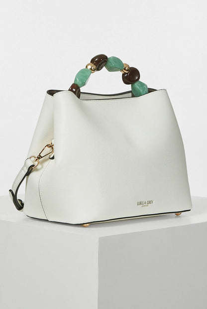 White bucket handbag with beaded handle and shoulder strap, gold-tone trim