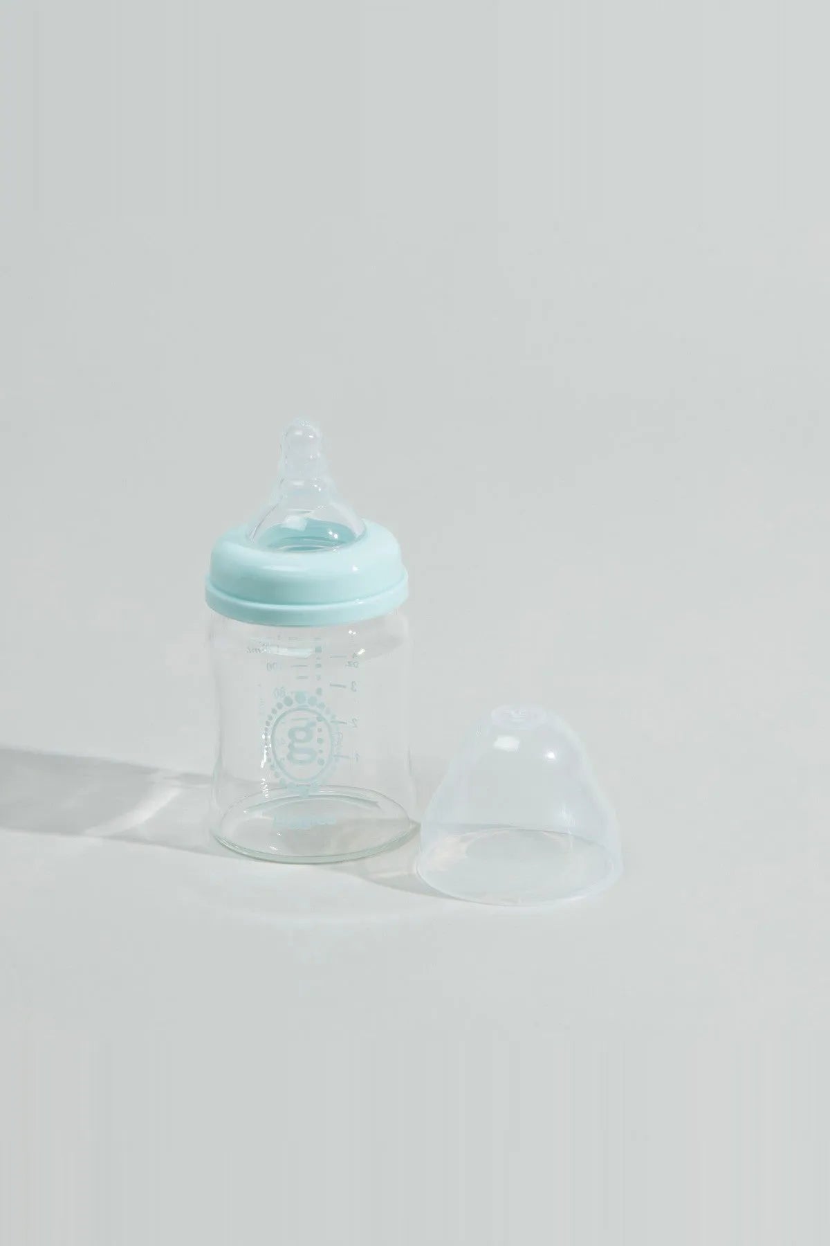 Baby bottle with blue cap, clear body, and soft silicone nipple