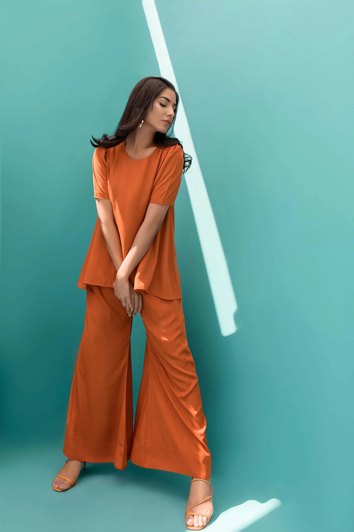 Orange velour tunic and wide-leg pants, side view with hand at waist