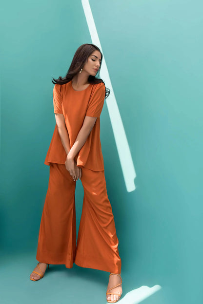 Orange velour tunic and wide-leg pants, side view with hand at waist
