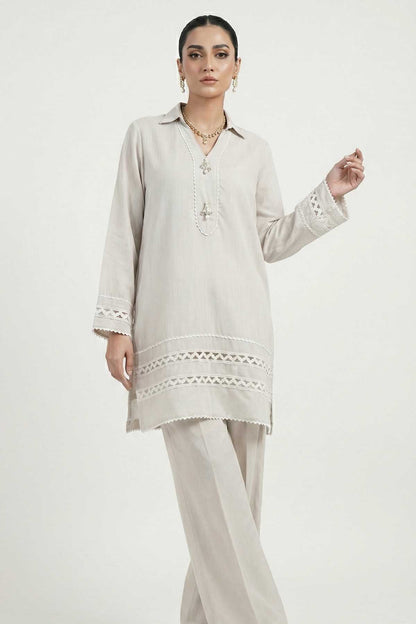 Light grey tunic with embroidered placket and lace hem, paired with straight trousers.