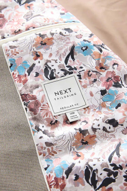 Floral-pattern fabric with NEXT tailoring label and fabric care tag, close-up.