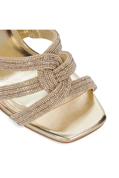 Gold rhinestone bow strap detail on heeled sandals with metallic footbed