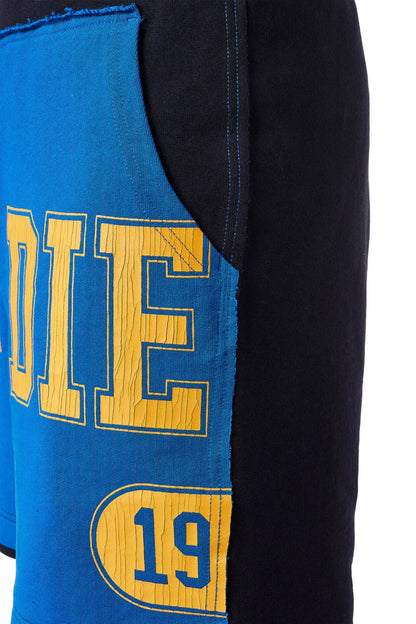 Close-up of blue Diesel shorts with yellow letter graphic and oval number patch