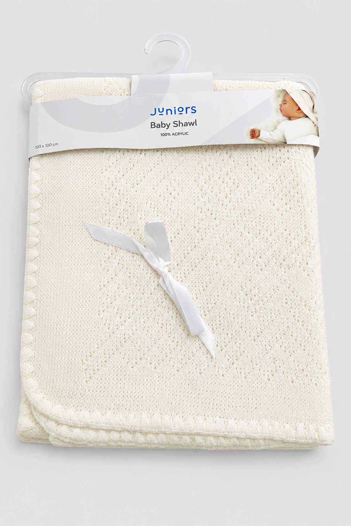 Folded baby shawl in white knit with decorative edge, shown on hanger packaging