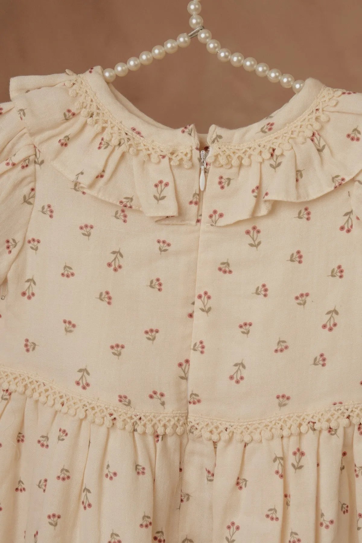 Cream floral baby dress detail: ruffled neckline and button placket with trim