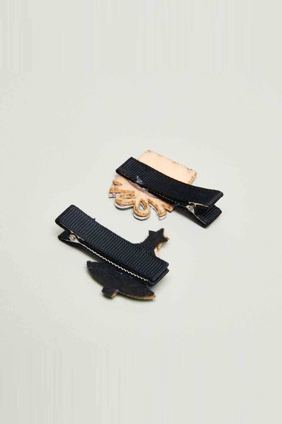 Two black hair clips with small star and candy decorations and tan backing