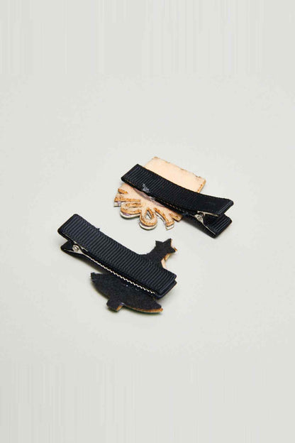 Two black hair clips with small star and candy decorations and tan backing