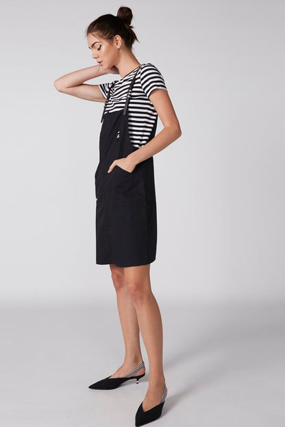 Black pinafore dress over striped tee, sleeveless bib and midi length