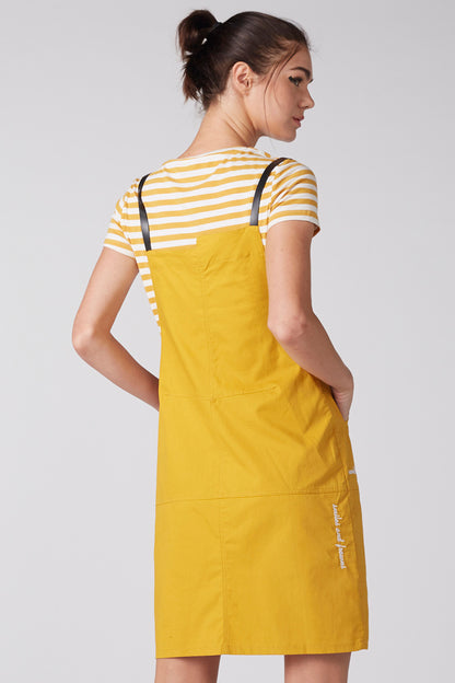 Back view of yellow bib overalls with black straps over striped short-sleeve T-shirt