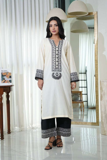 Embroidered cream kurta with black V-neck and cuffs, paired with black pants