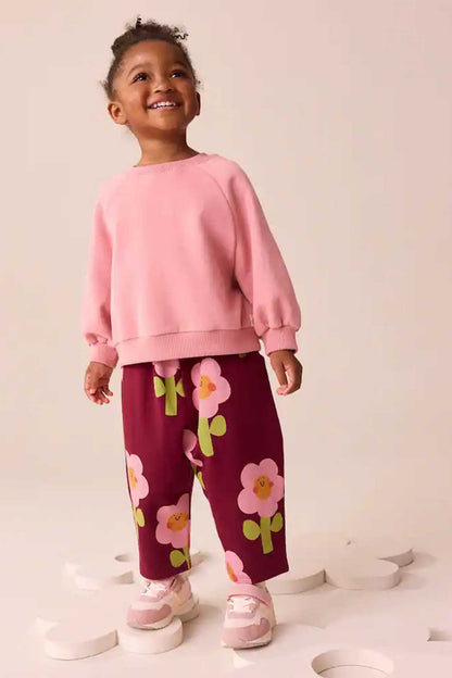 Kids burgundy floral pants with elastic waist, standing full-body view