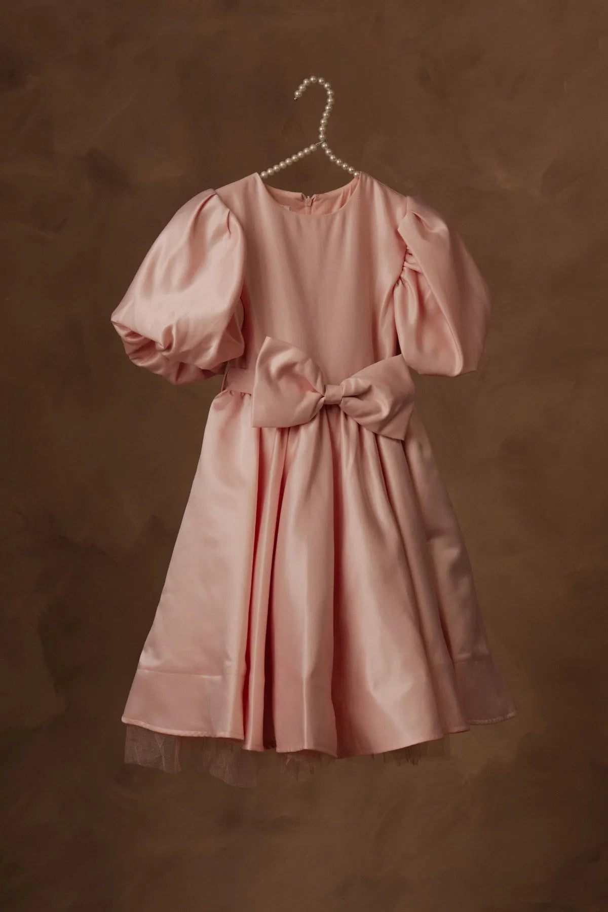 Pink puff-sleeve dress with gathered waist bow and flared skirt, hanging view.