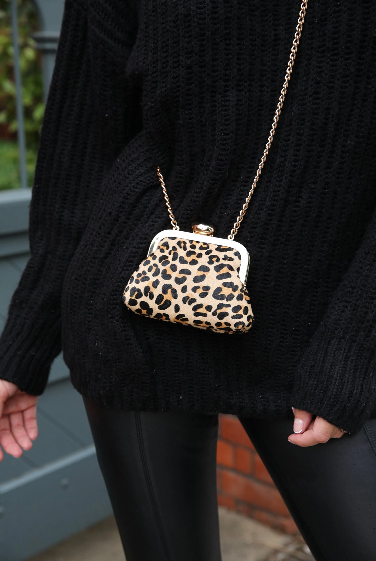 Leopard-print mini handbag with gold chain and clasp, worn over knit sweater