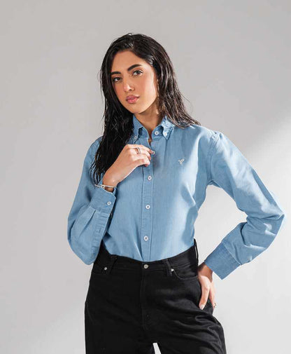 Fitted light blue button-up shirt with chest logo, long sleeves, and black jeans
