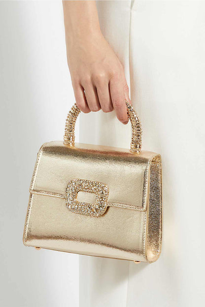Gold mini handbag with beaded top handle and jewel front clasp, held by hand