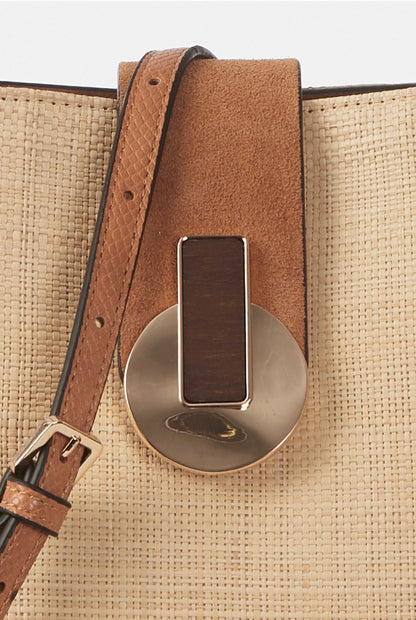Brown leather strap detail with rectangular metal clasp on tan woven handbag