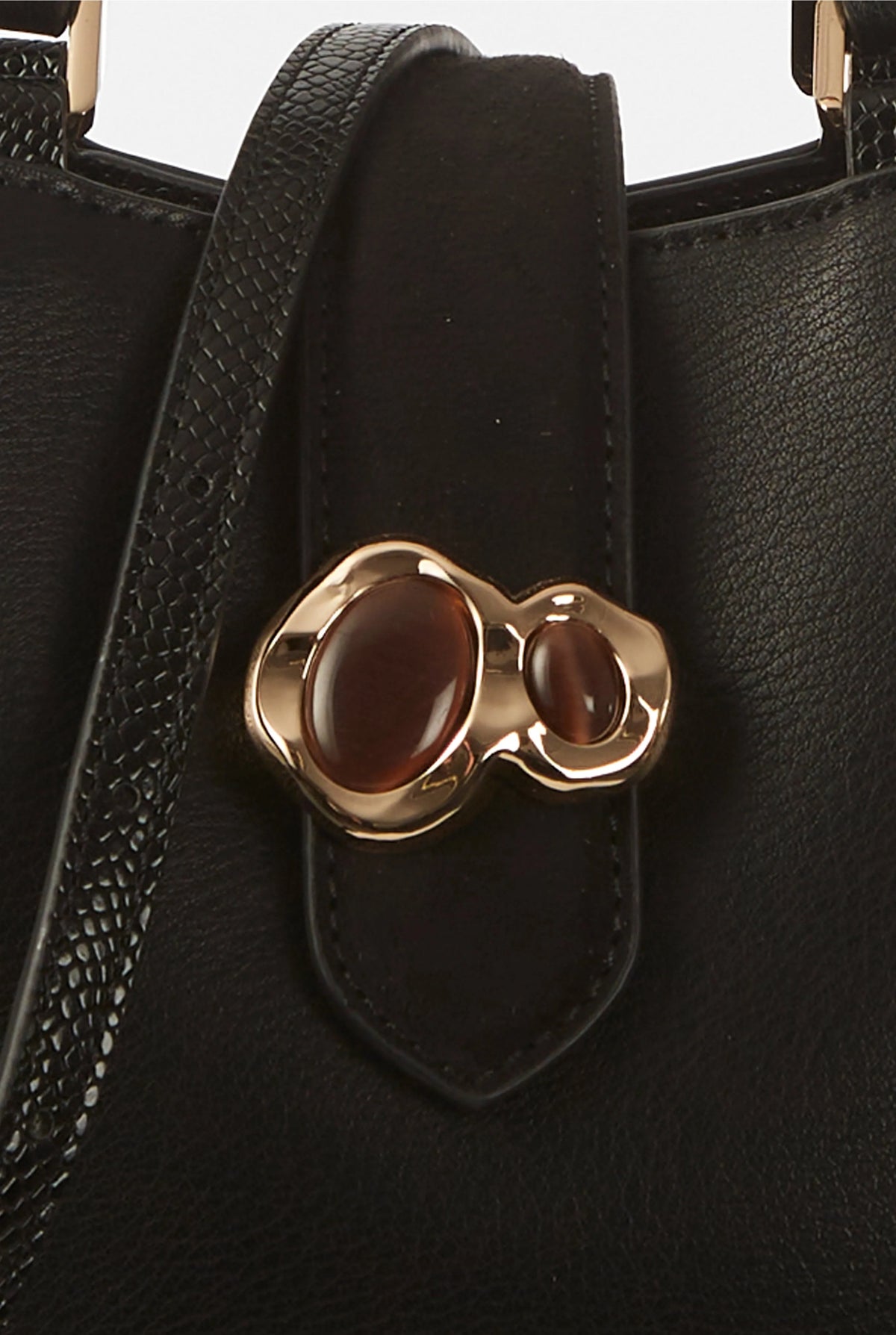 Black handbag front pocket with gold-tone clover clasp and textured trim