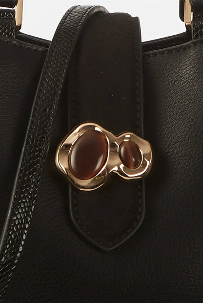 Black handbag front pocket with gold-tone clover clasp and textured trim