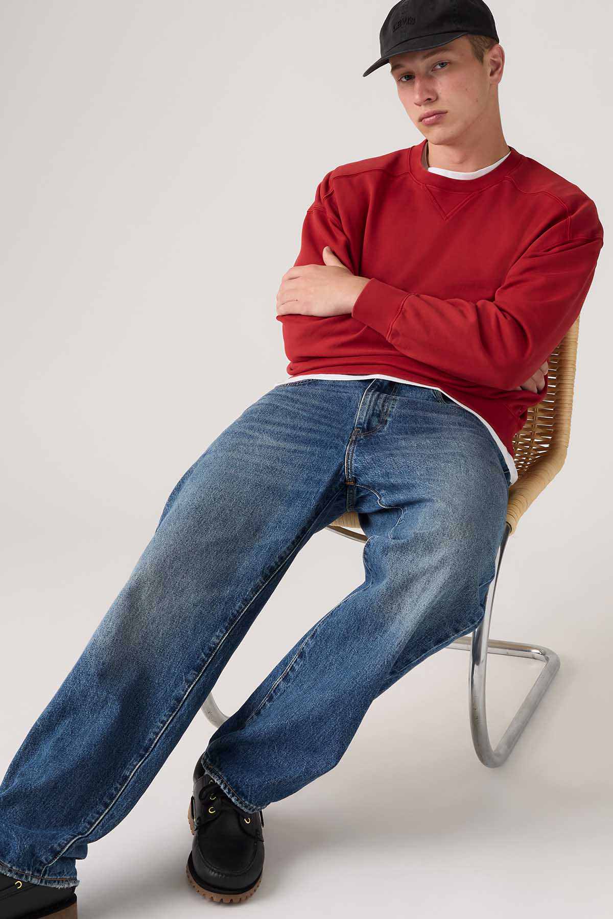 Levi's red crewneck sweatshirt, long sleeves and white trim, model seated pose